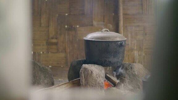 在木墙背景上的篝火上用锅煮食物在传统的亚洲村落里用水壶烧着晚餐