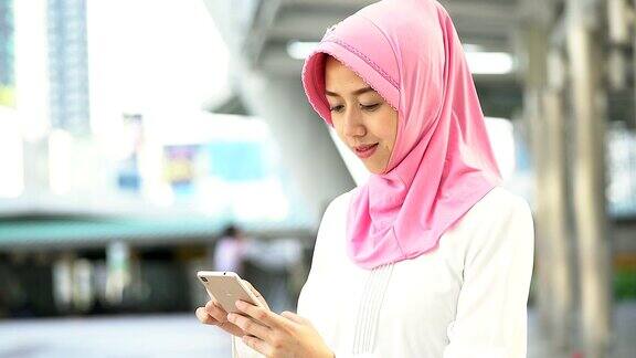 年轻的穆斯林妇女在城市玩手机的肖像穆斯林人肖像