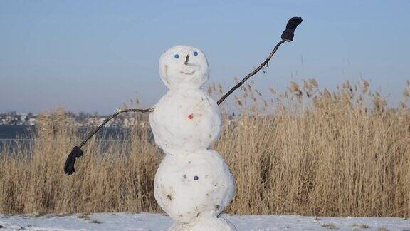 快乐滑稽的雪人杂技演员倒立在头上背景上有一根芦苇