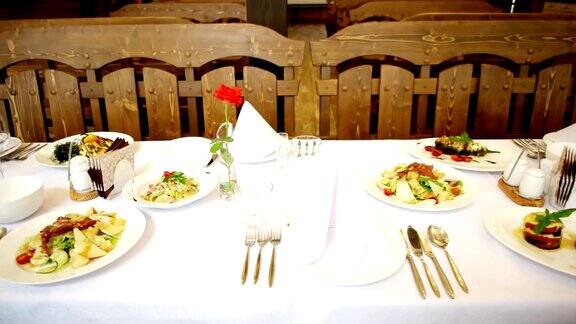 在餐厅的宴席上盘子和食物放在桌子上刀叉、玻璃杯、刀具躺在盘子旁边食物放在漂亮的白色桌子上