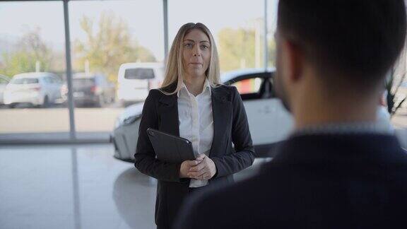汽车销售员与男顾客在汽车经销商交谈