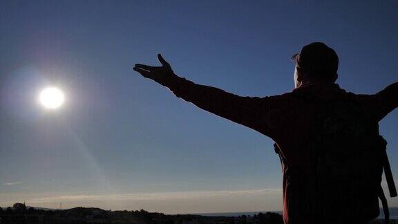 人站在山顶看着冉冉升起的太阳在拂晓的时候向天空举起双手