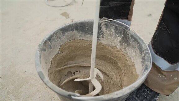 在桶里搅拌溶液用电动搅拌机搅拌混凝土灰泥