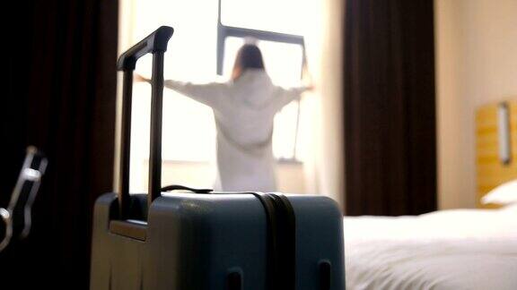 一个女人拿着行李在酒店房间里拉开窗帘