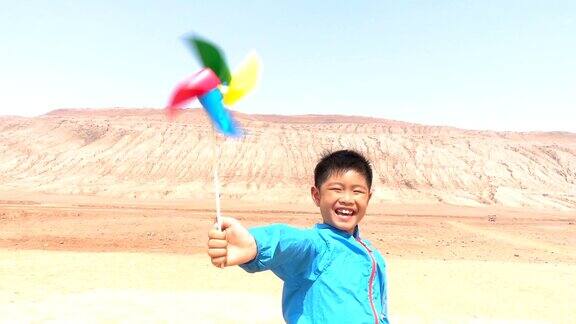 一个亚洲男孩在吐鲁番火焰山玩风车