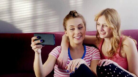 两个年轻女人在视频聊天积极的情绪在手机镜头前挥挥手