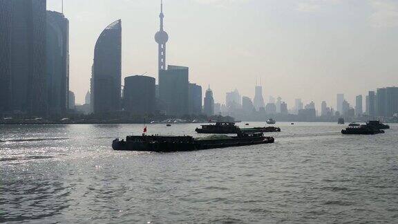 从渡轮、摩天大楼和地标建筑上观看上海外滩蓝天背景货船在黄浦江上航行4K视频慢镜头