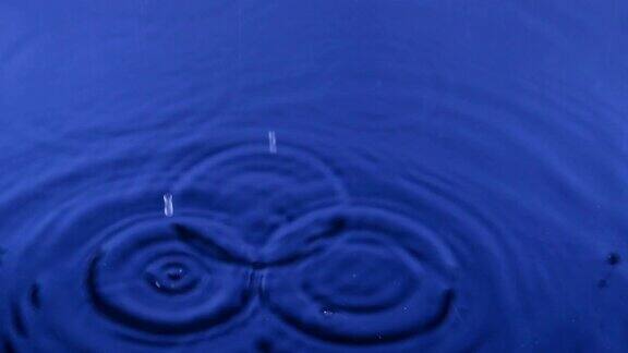 特写雨滴落在蓝色的水中