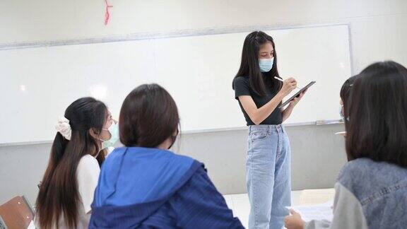 女大学生在“社交距离”教室里间隔着座位以防止传染性疾病