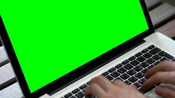 在笔记本电脑上打字的人的手绿色屏幕特写