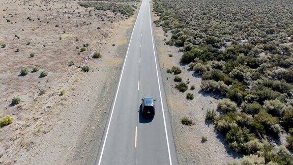 汽车在尘土飞扬的干燥的沙漠中行驶在柏油路上的鸟瞰图