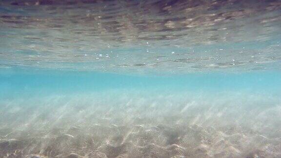 水下沙海水波搅动着沙子蓝绿色的海色阳光穿过海洋抽象背景慢动作无缝循环