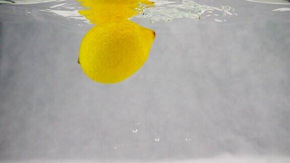 一只柠檬带着泡泡慢镜头掉进水里果实孤立在白色背景上