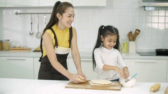 母亲和女儿在家里的厨房进行在线烘焙课程