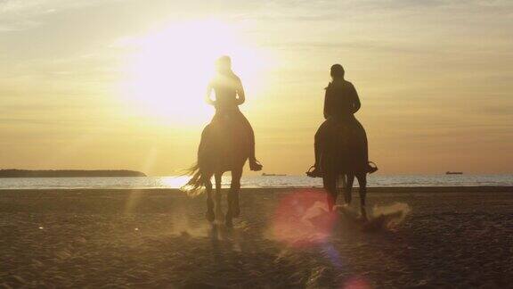两个年轻女人在海滩上骑马的剪影