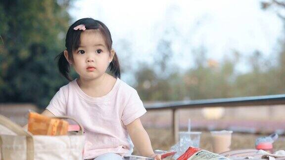 亚洲小女孩在公园野餐吃草莓