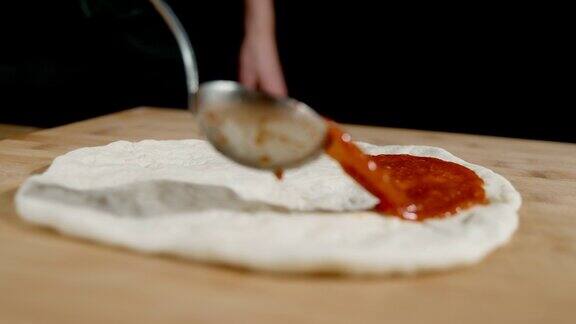 厨师将番茄酱倒在披萨面团上
