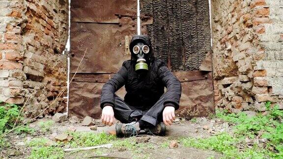 一个戴着防毒面具穿着黑色连帽衫的人坐在一座废弃建筑的背景上后启示录世界跟踪者概念核化学战争幸存者缓慢的运动