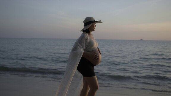 一名孕妇在沙滩上散步时抚摸着自己的肚子
