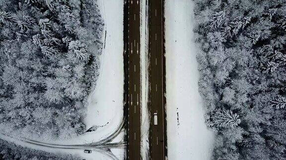 4k在冰冻的冬季森林里驾驶汽车飞过道路空中俯视图