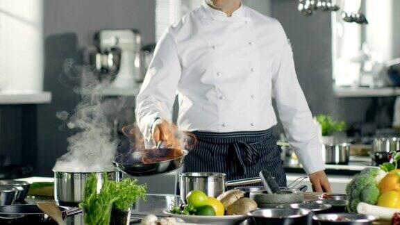专业厨师在平底锅上烧油烧过的烹饪风格他在一个现代厨房工作里面有很多食材