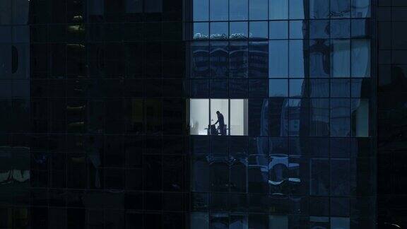 鸟瞰图镜头:从外面到办公大楼商人使用手机站在办公室窗户旁金融商业区摩天大楼的美丽撤退的飞行镜头