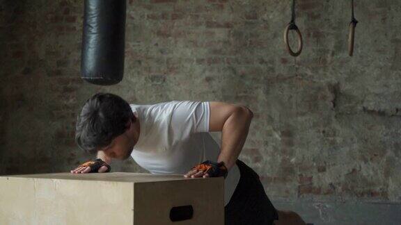 一个男人在健身房里从一个木箱子里做俯卧撑