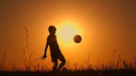 小男孩足球运动员剪影练习用球日落黄金时慢动作