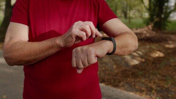 老跑步者开始点击智能手表上的触摸屏跟踪距离检查脉搏