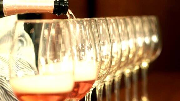 侍酒师将玫瑰葡萄酒倒入一排水晶酒杯中