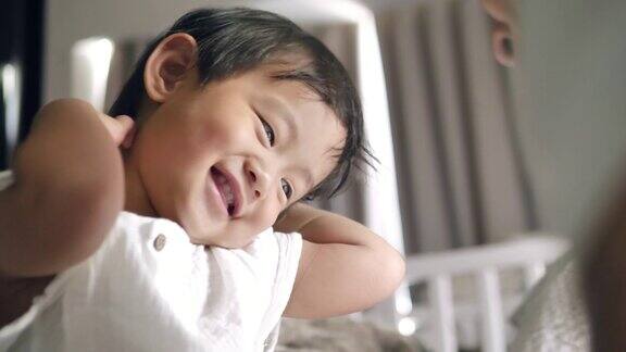 亚洲男婴在家里的卧室里和妈妈一起笑和玩