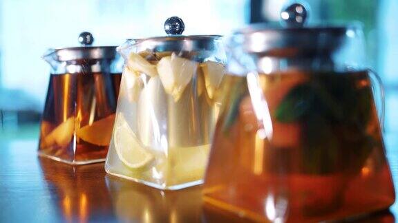 茶壶里的水果茶花草茶茶饮料特写镜头三个玻璃茶壶里面有不同的水果和草药五颜六色的自制茶