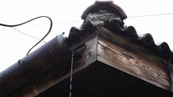 暴风雨过后水流穿过屋顶上生锈的旧排水沟