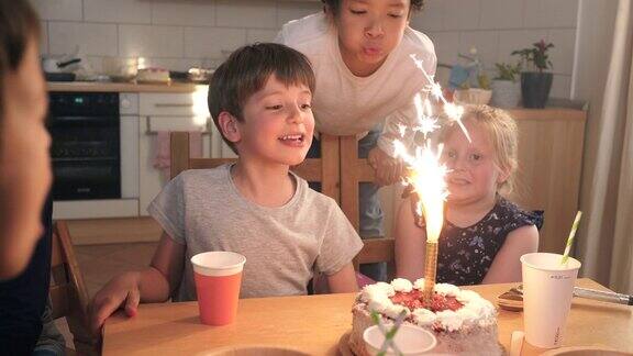 孩子们在生日蛋糕上吹着亮晶晶的烟火蜡烛