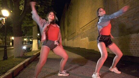 两个年轻女子晚上在城市公园跳街舞青年亚文化当代的编排常平架枪