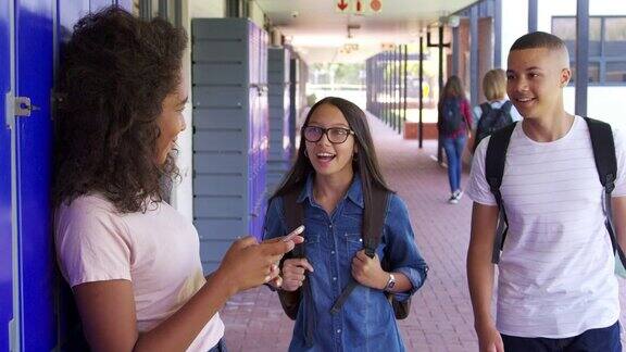 三个十几岁的朋友在学校走廊里聊天慢镜头