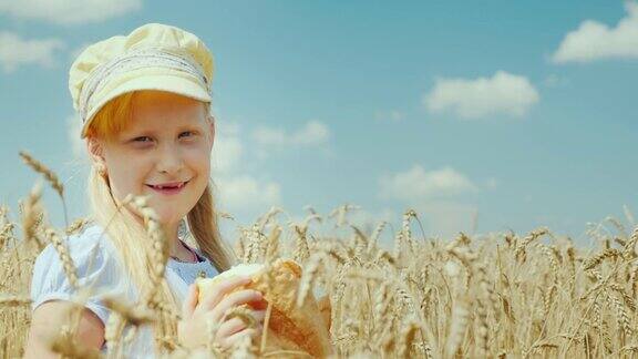 一个拿着面包的女孩站在麦田里看着摄像机
