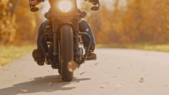 摩托车车轮特写秋天的路树叶飞舞