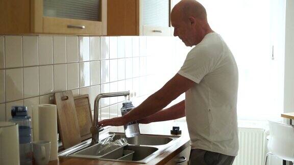 高级男子在厨房装运动水瓶