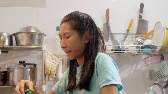 快乐的亚洲女孩在厨房做饭的同时测试食物生活方式