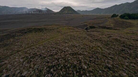 无人机低空飞行俯冲熔岩场黑色火山沙云天空山谷