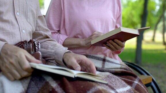 退休夫妇一起看书坐在公园长椅上养老休闲时光