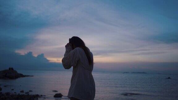 亚洲女人走在海滩上看着大海在日落