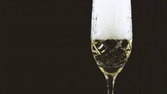 在黑色背景下香槟正倒入水晶玻璃中水晶香槟杯泡沫飘逸4k原始视频60帧秒