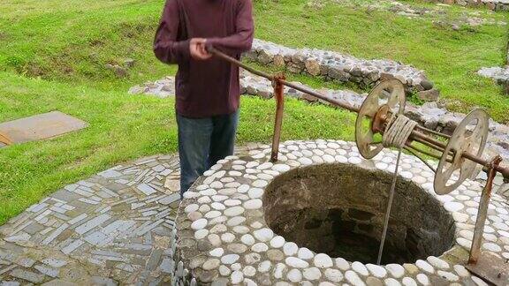 人们从历史悠久的喷泉井里取水绳子桶容器