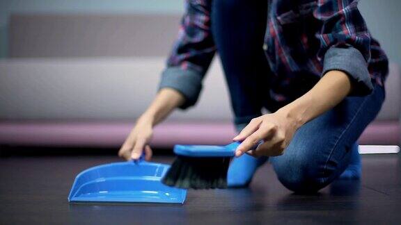 年轻的家庭主妇用刷子和簸箕清洁一尘不染的地板非常卫生