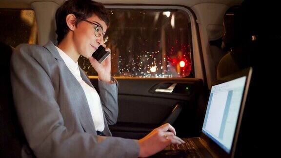 年轻积极有抱负的女商人晚上开车在后座上工作