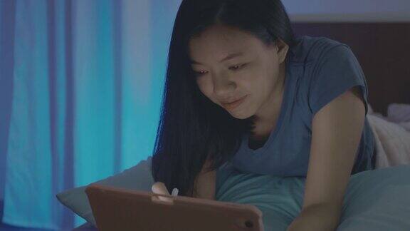 亚洲女商人在家用平板电脑工作晚上在卧室的床上感觉很快乐社交距离是阻止Covid-19冠状病毒疾病传播的感染控制行动
