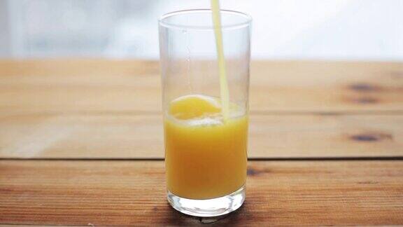 橙汁倒进木桌上的玻璃杯里