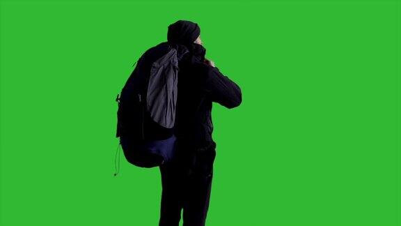 年轻男性徒步旅行者与一个背包看向远方-绿色的屏幕